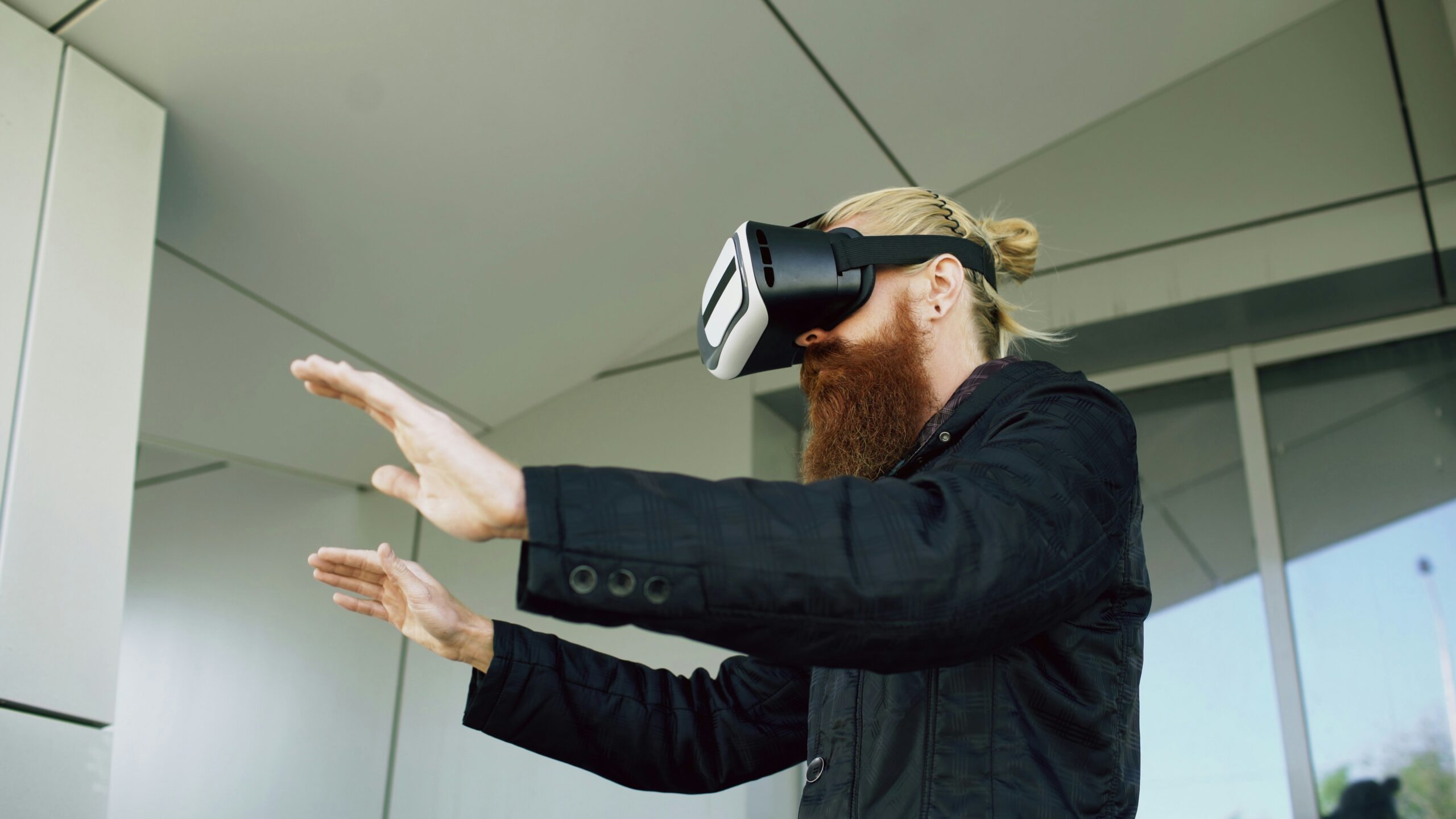 Young bearded man using virtual reality headset for 360 VR experience while walking down city street outdoor