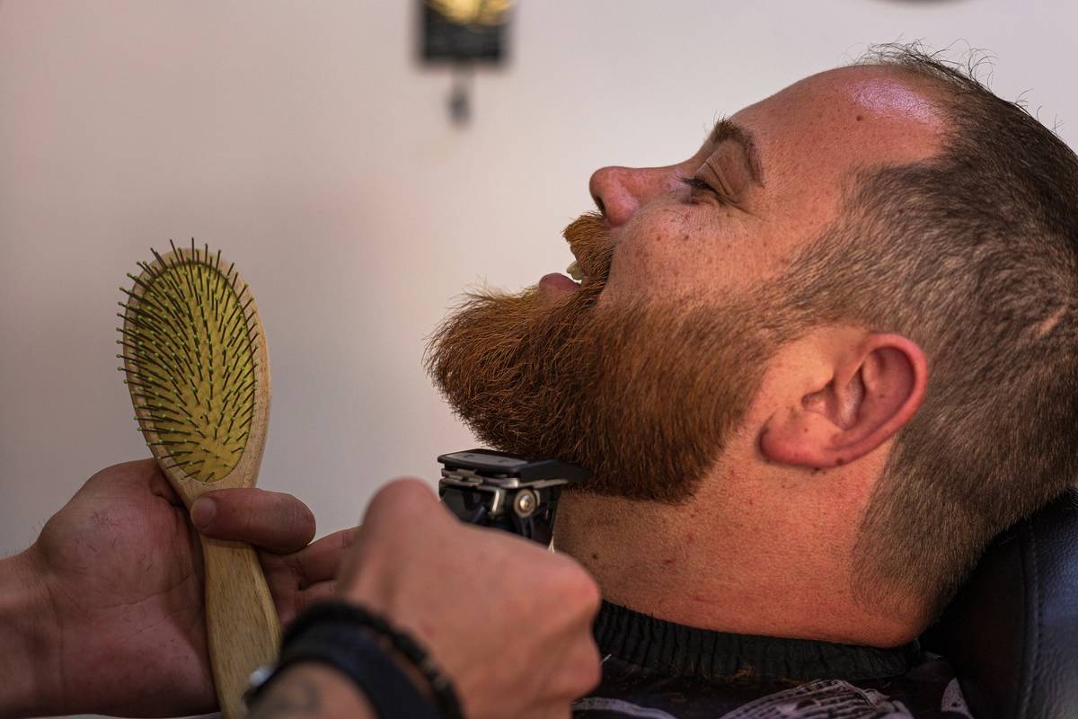 A man styling his beard with products from a grooming kit