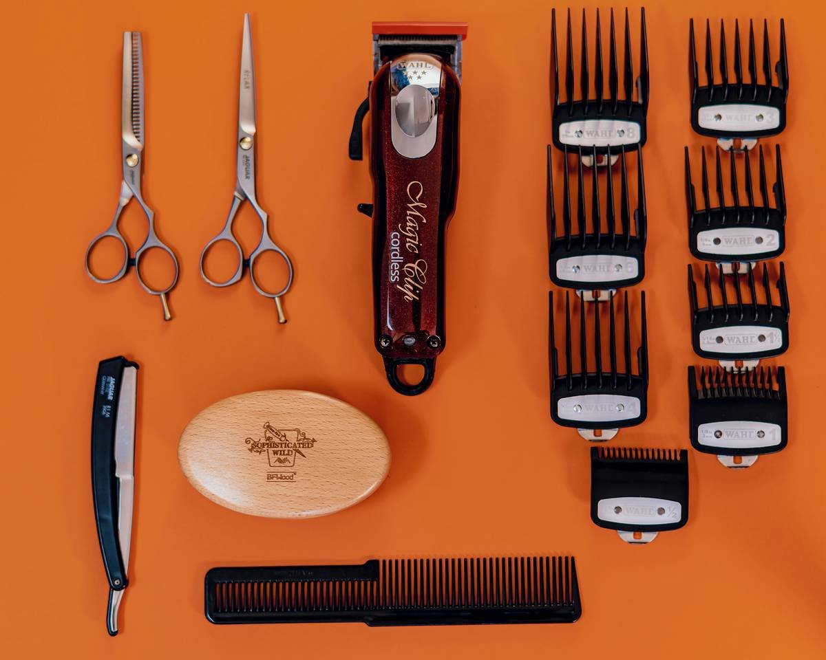 A high-quality photo showing a complete beard pampering kit with oil bottles, combs, and scissors on a wooden table